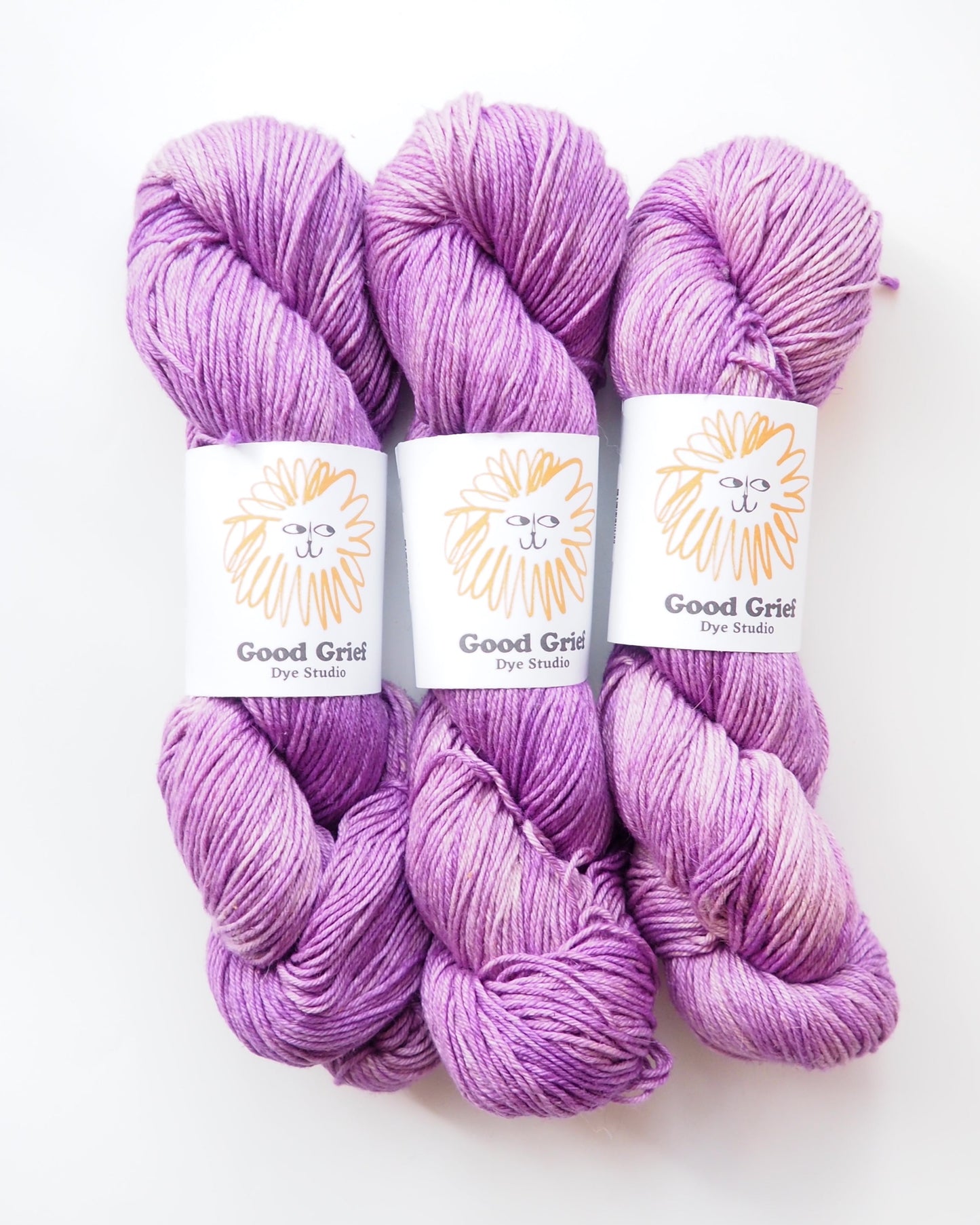 Three skeins of purple yarn with 'Good Grips' labels on a white background