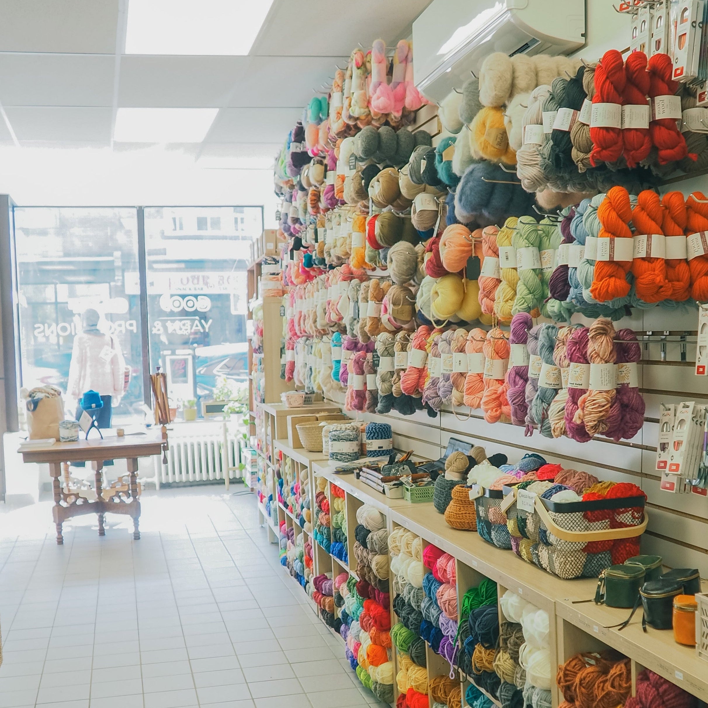 Store interior with shelves filled with colorful yarn and knitting supplies.