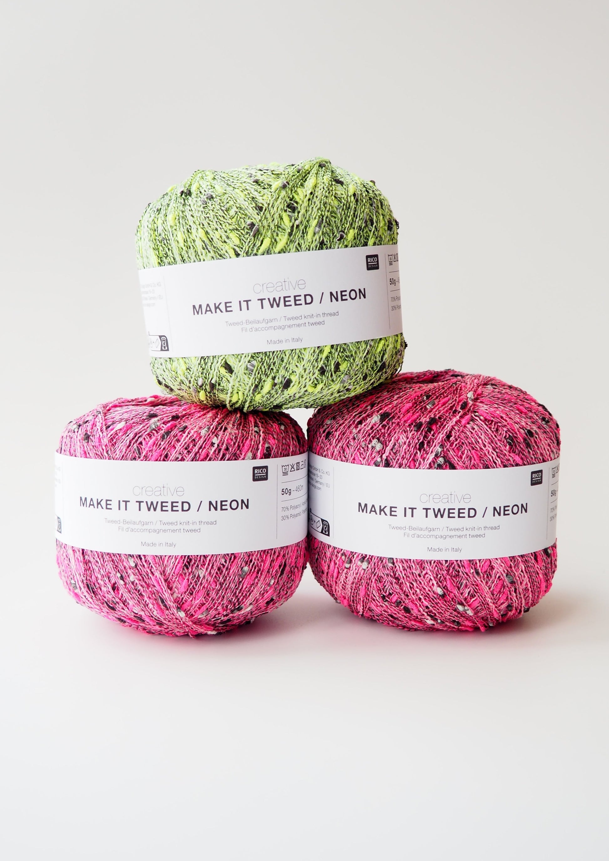 Image showcasing three balls of Rico Creative Make It Tweed yarn (one green and two pink), a versatile blend that adds tweed neps to any project. The yarn features a range of neon colours including green and pink, providing texture and depth to knitted or crocheted items.