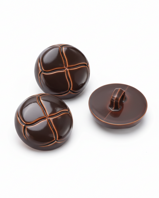 Three brown buttons with decorative patterns on a textured surface