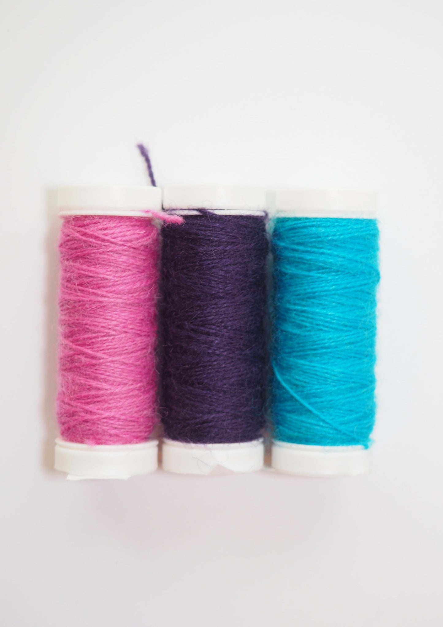 image of three spools of jawoll reinforcement thread. one pink, one purple, and one turquoise