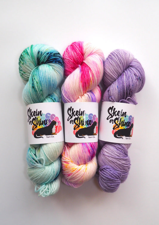 Three skeins of hand-dyed yarn in vibrant colors: Skein or Shine Sock collection