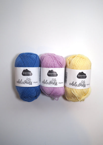 an image of three balls of kremke soul wool edelweiss in blue, lilac, and baby yellow.