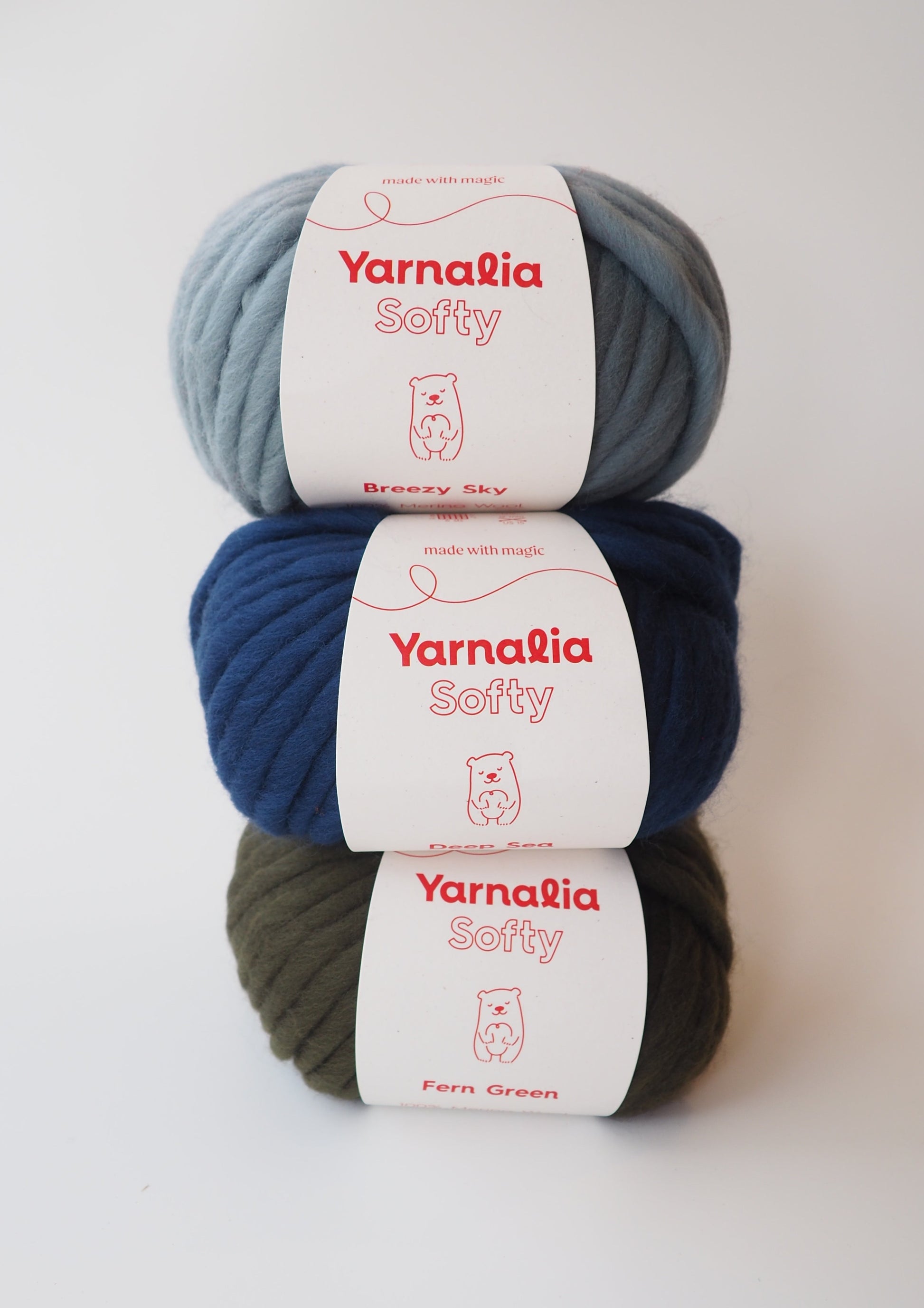Yarnalia Softy Yarn: Three balls in light blue, dark blue, and olive colorways, showcasing the soft and squishy texture